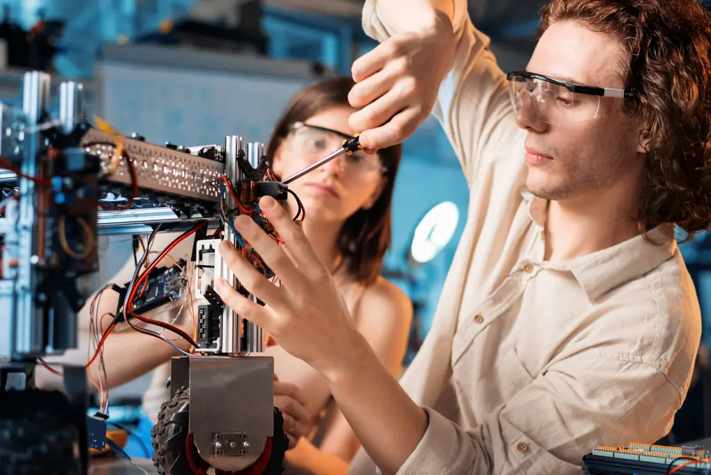 Apprentis réglant un équipement robotisé en laboratoire